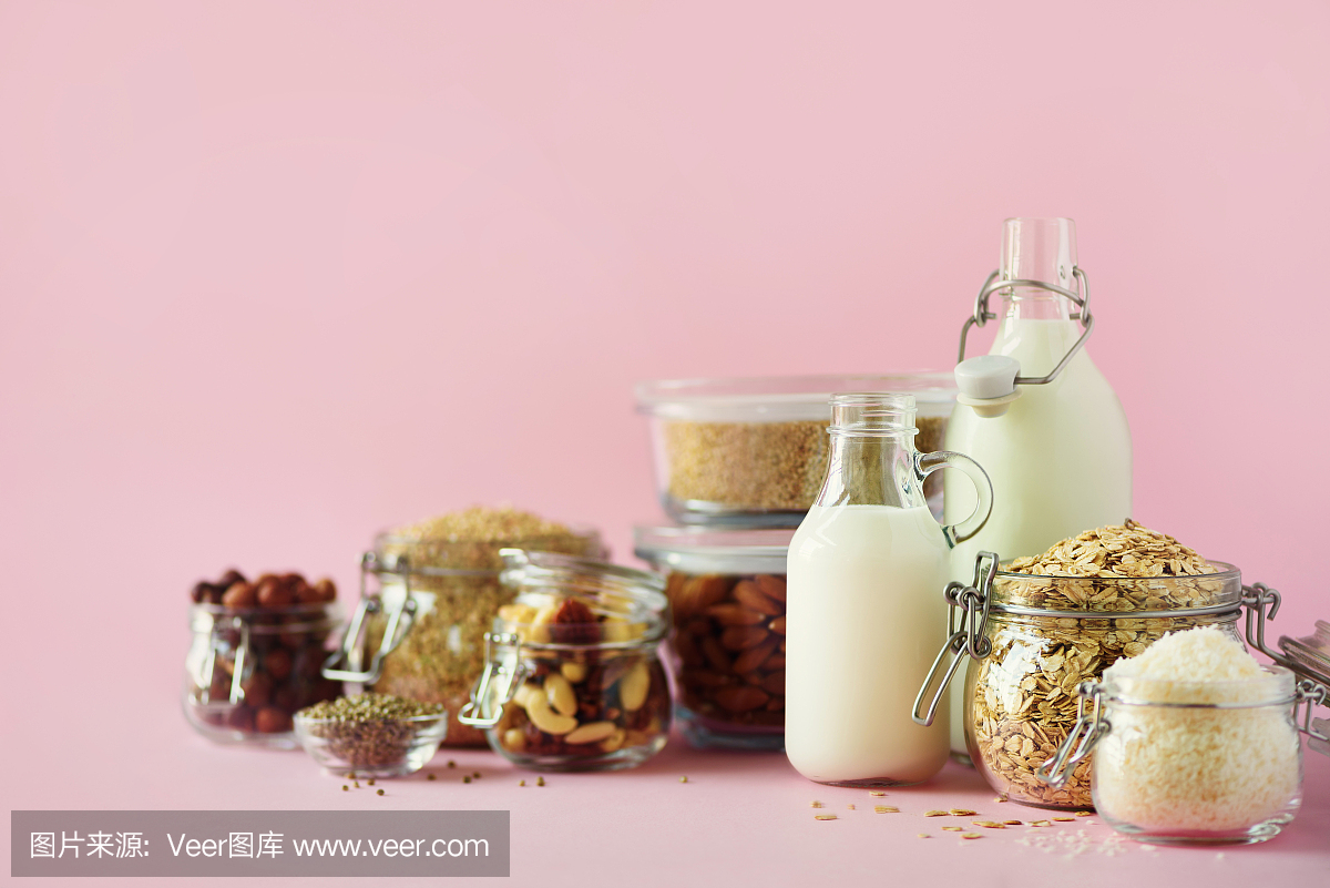 素食代替牛奶。玻璃瓶與非乳制品的牛奶和原料在粉紅色的背景與復(fù)制空間。清潔飲食,無乳制品,素食,防過敏,健康的食品理念